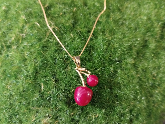 Gold necklace with red berries on a green textured background
