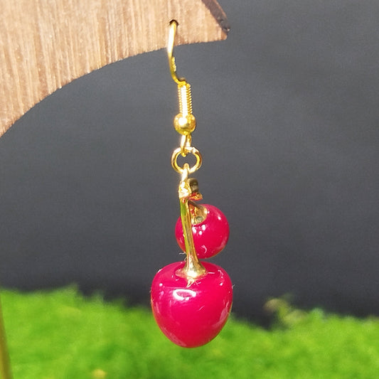 Gold earrings with pink beads on a wooden stand
