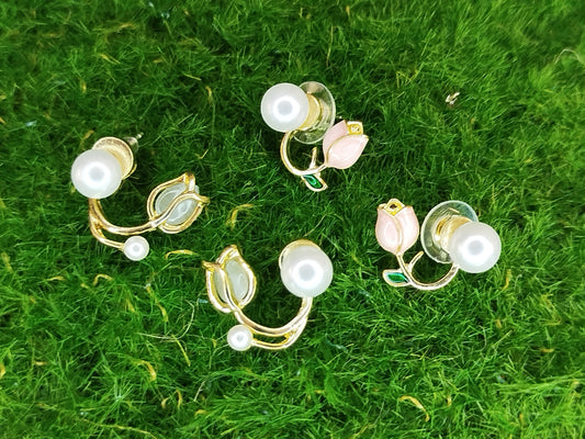 Gold and pearl earrings on a green grass background