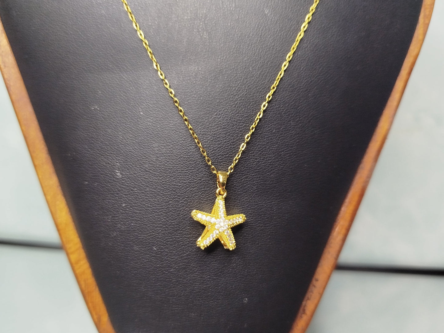 Gold star-shaped pendant necklace on a black mannequin bust.