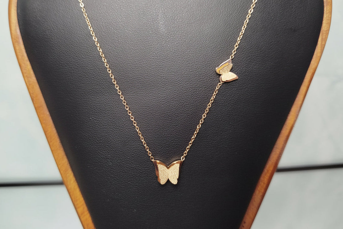Gold butterfly necklace on a black jewelry display