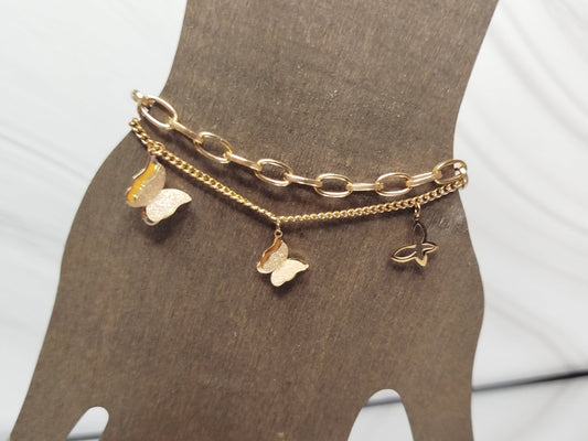 Gold chain bracelet with butterfly charms on a mannequin hand.