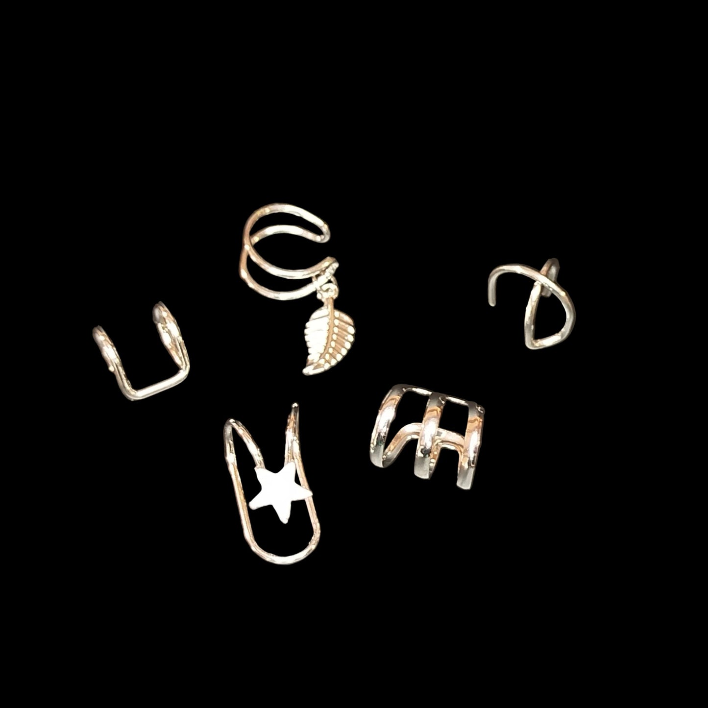 Set of silver ear cuffs on a dark gray background