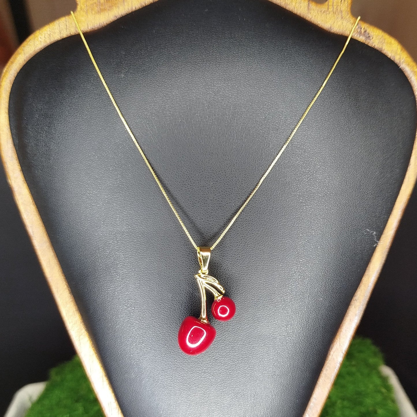 Necklace with a red pendant on a black display stand.