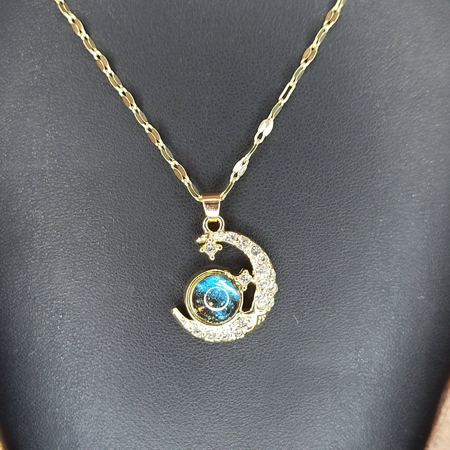 Gold necklace with a moon and star pendant featuring a blue gemstone