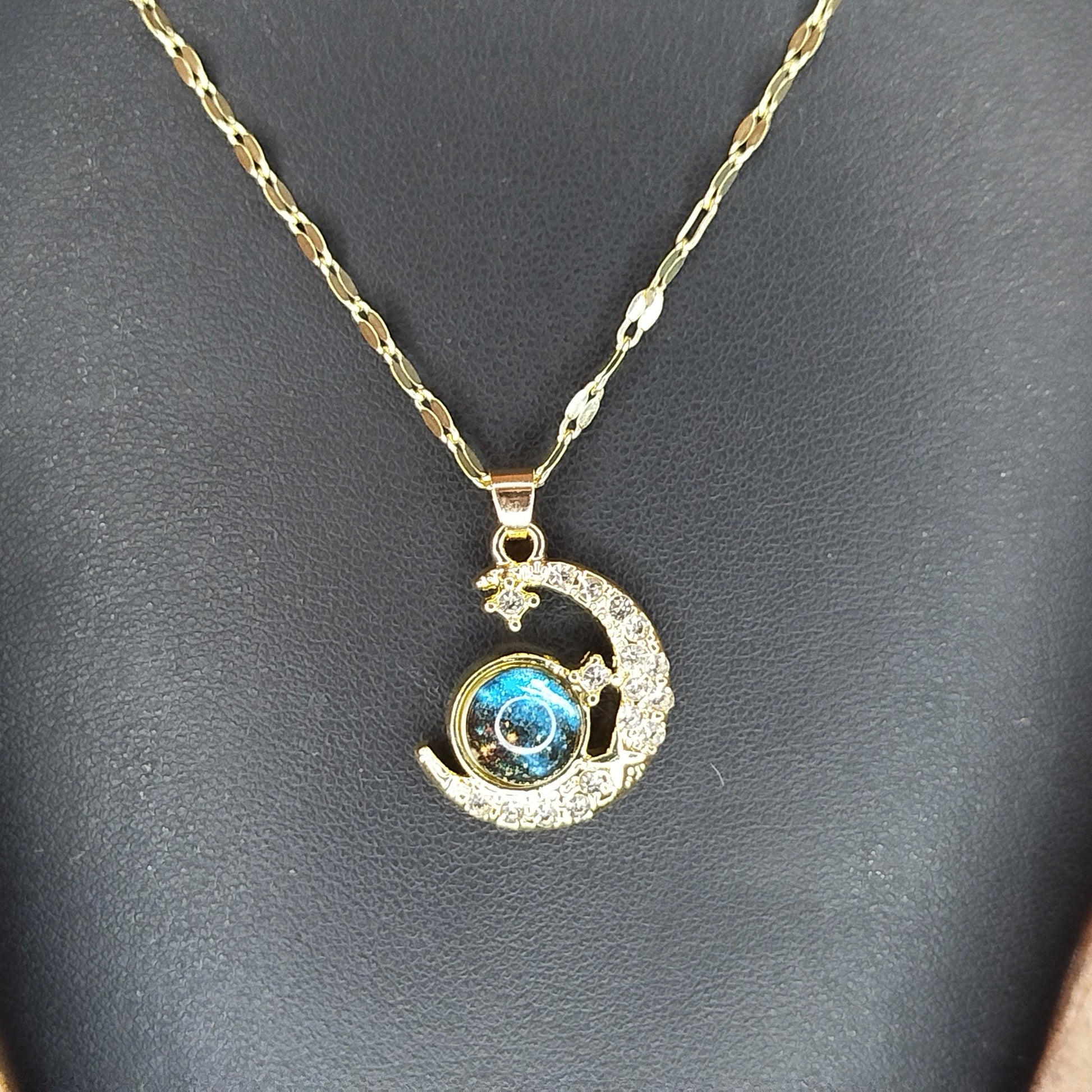 Gold necklace with a moon and star pendant featuring a blue gemstone