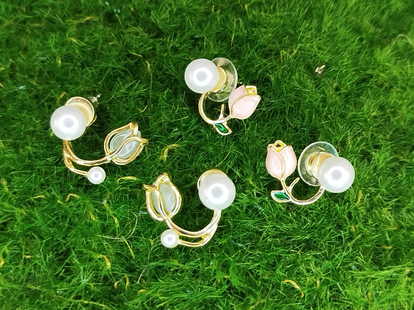 Gold and pearl earrings on a green grass background