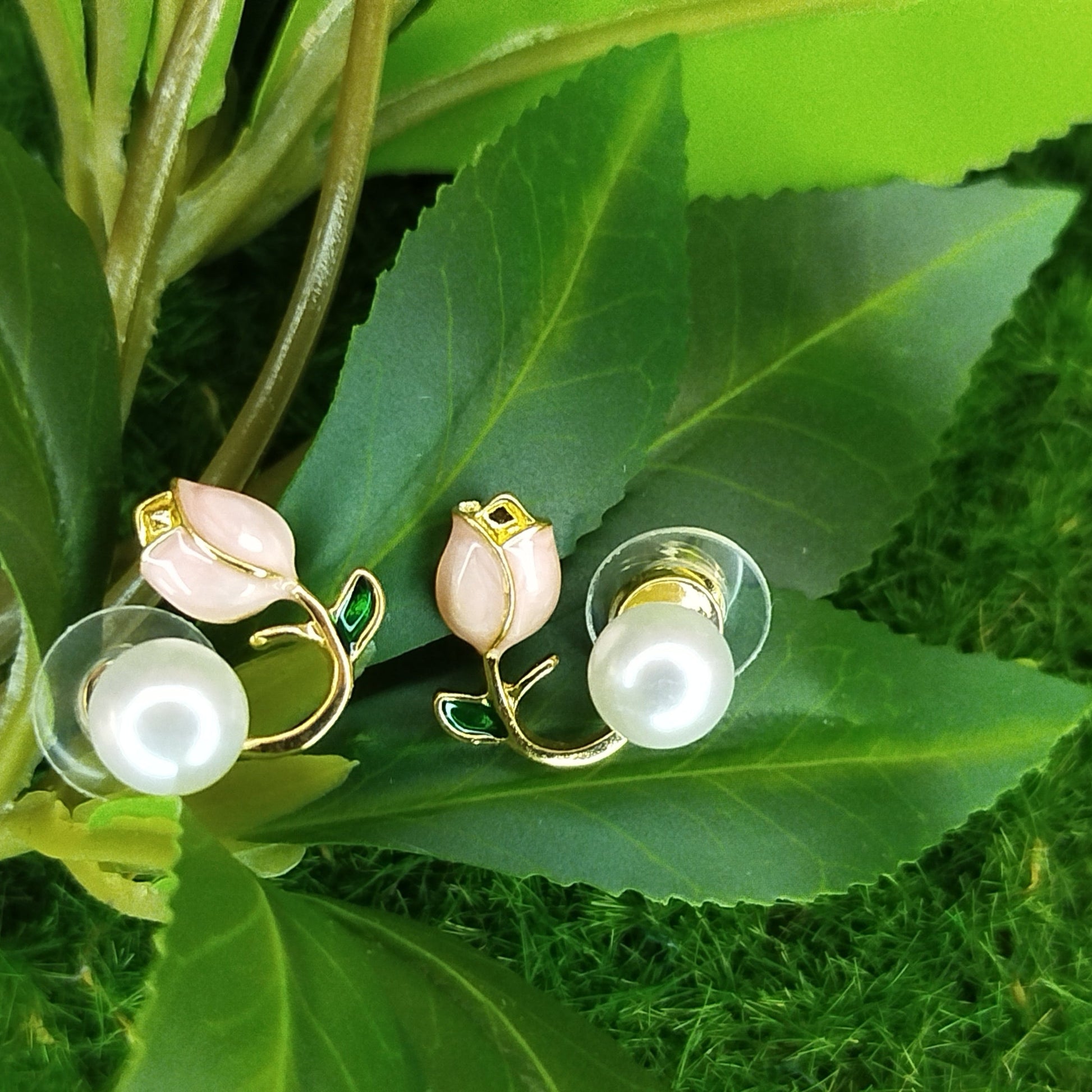 Pearl earrings with gold accents on a green leaf background