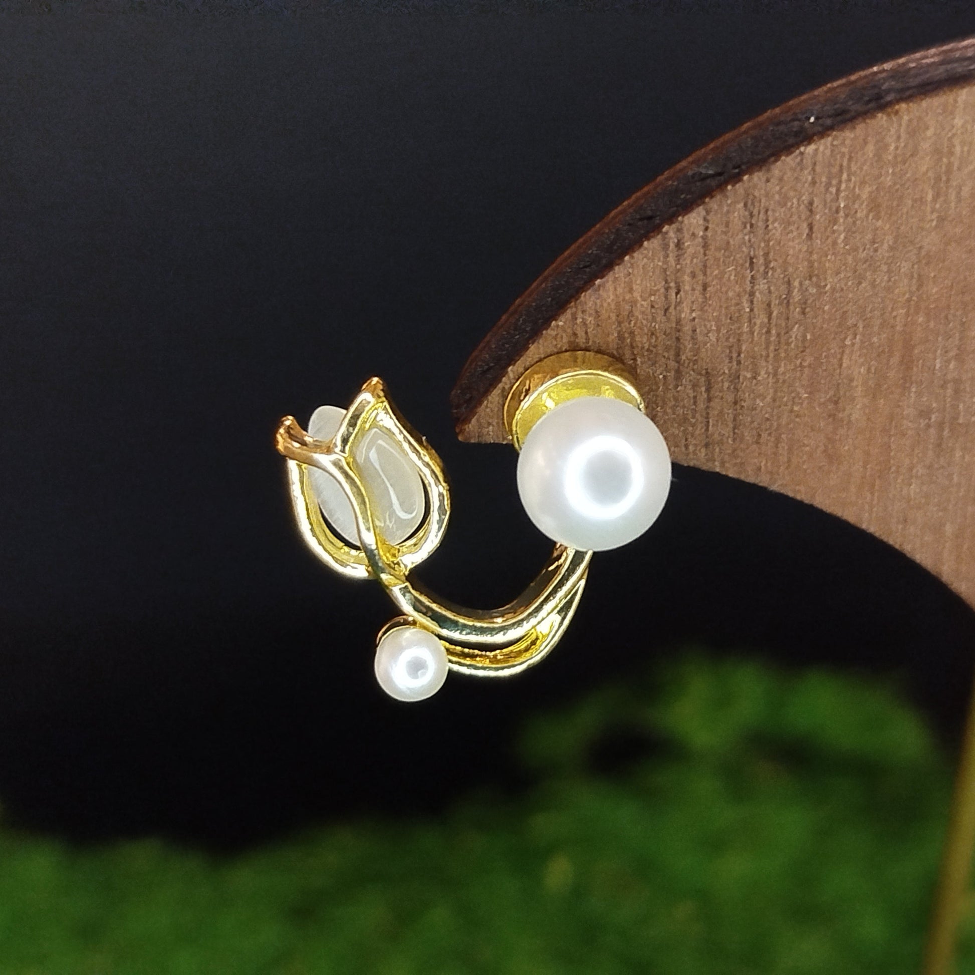 Pearl earrings with gold accents on a wooden stand