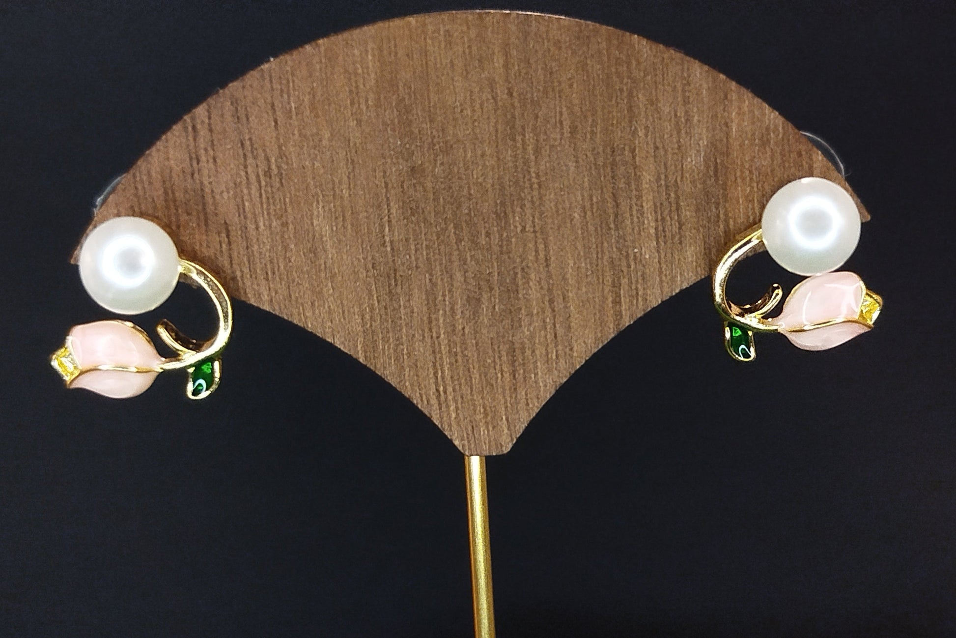 Pair of pearl earrings on a wooden display stand with a dark background
