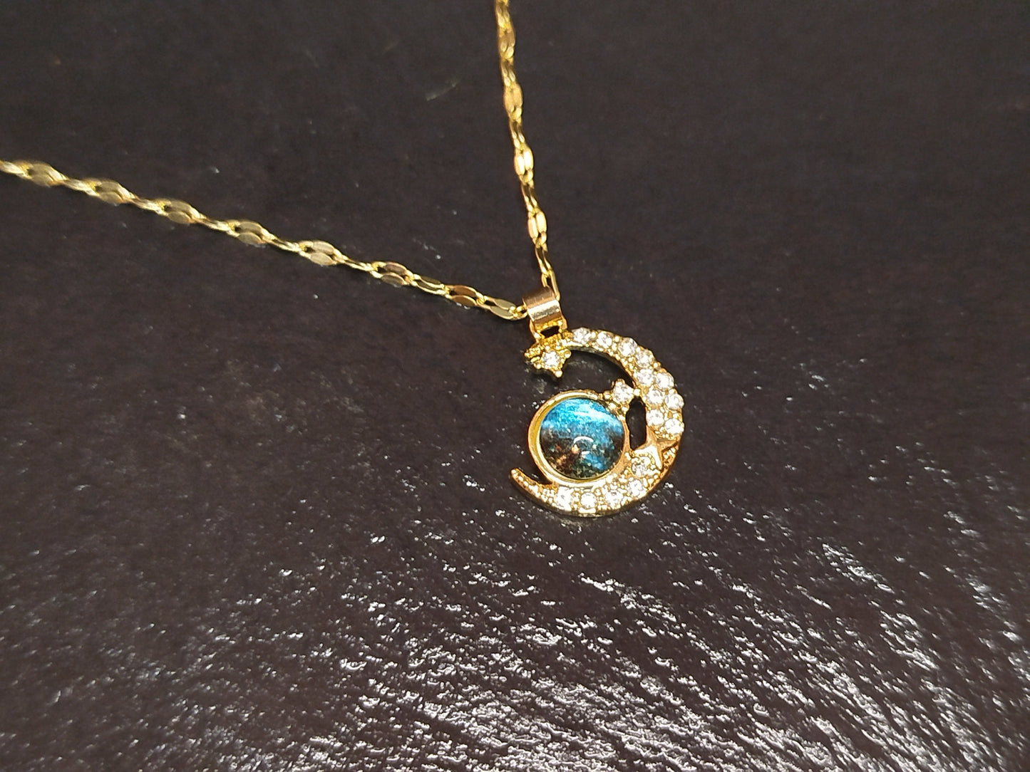 Gold necklace with a pendant featuring a blue gemstone
