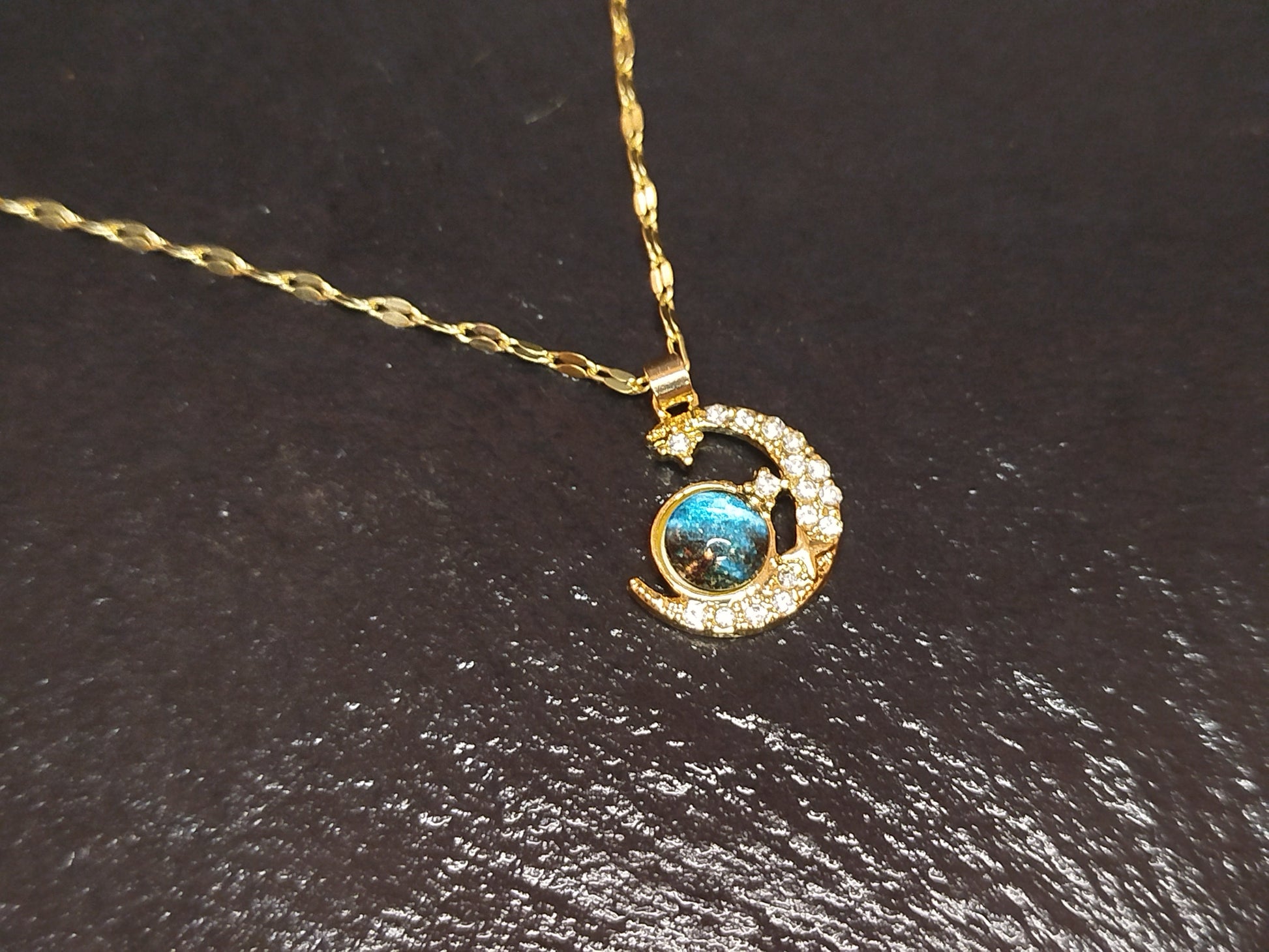 Gold necklace with a pendant featuring a blue gemstone