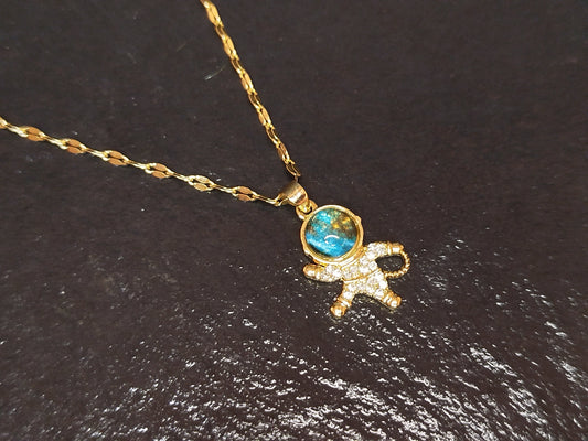Gold necklace with a turquoise gemstone and small figure pendant