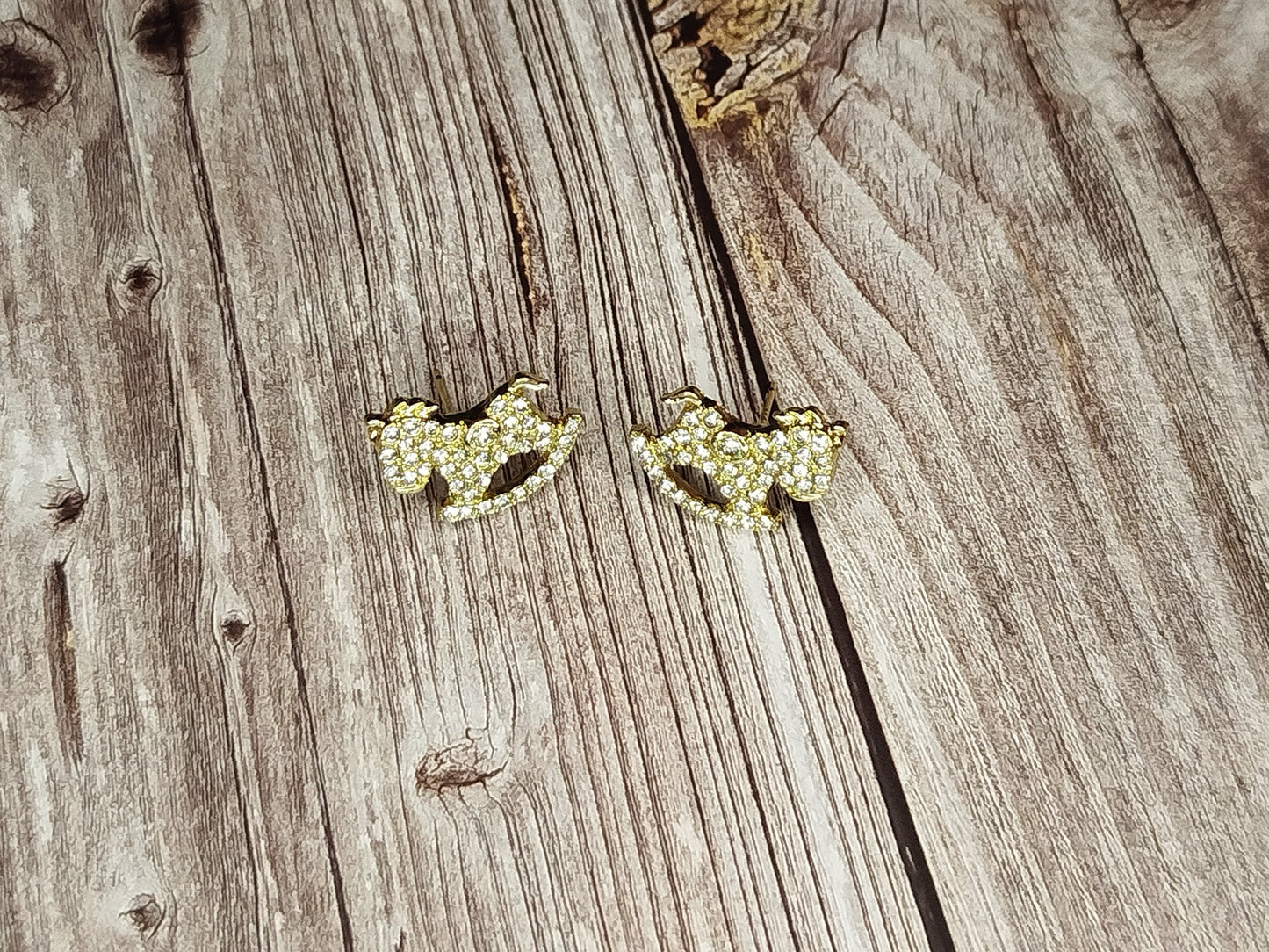 Pair of gold earrings on a wooden surface
