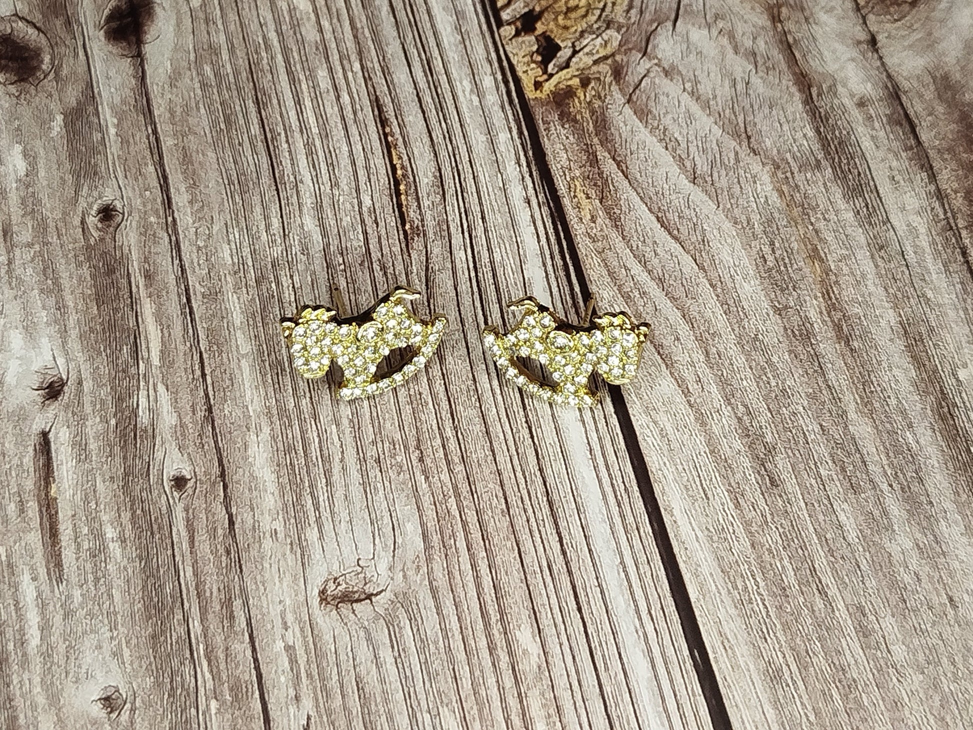 Pair of gold earrings on a wooden surface