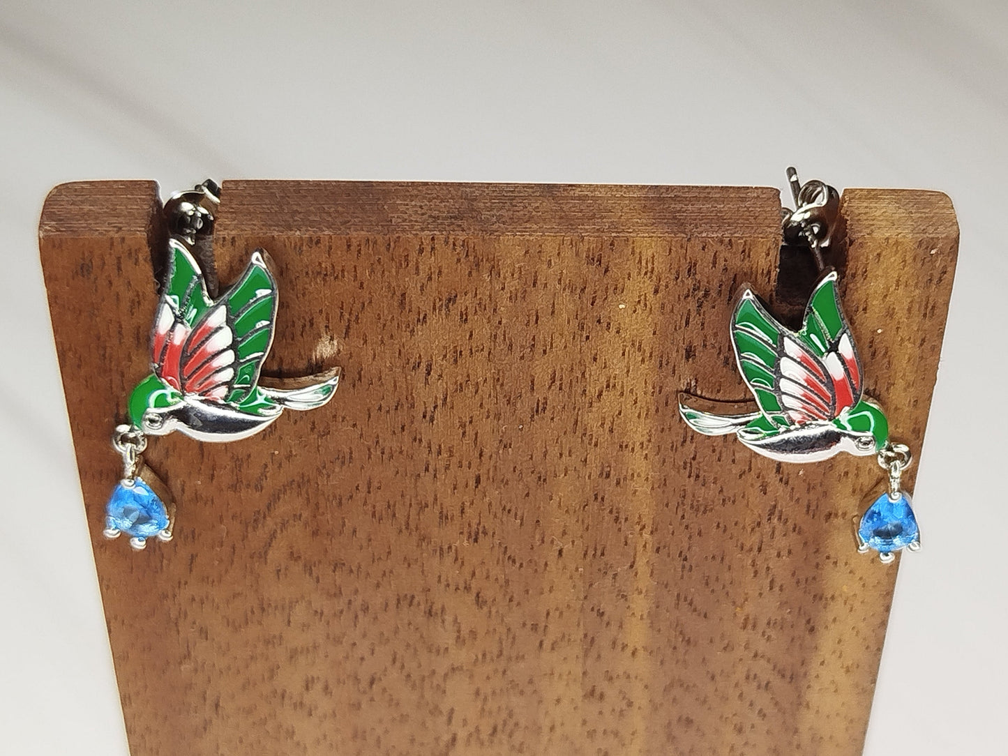 Bird-shaped earrings on a wooden stand