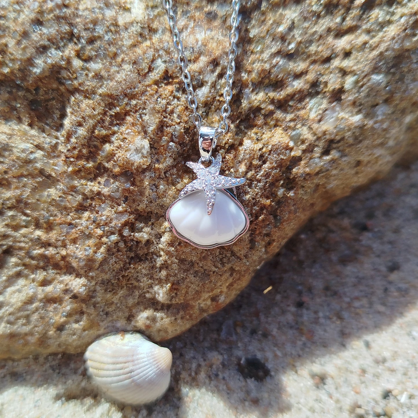 Necklace with a shell pendant on a rock and sand