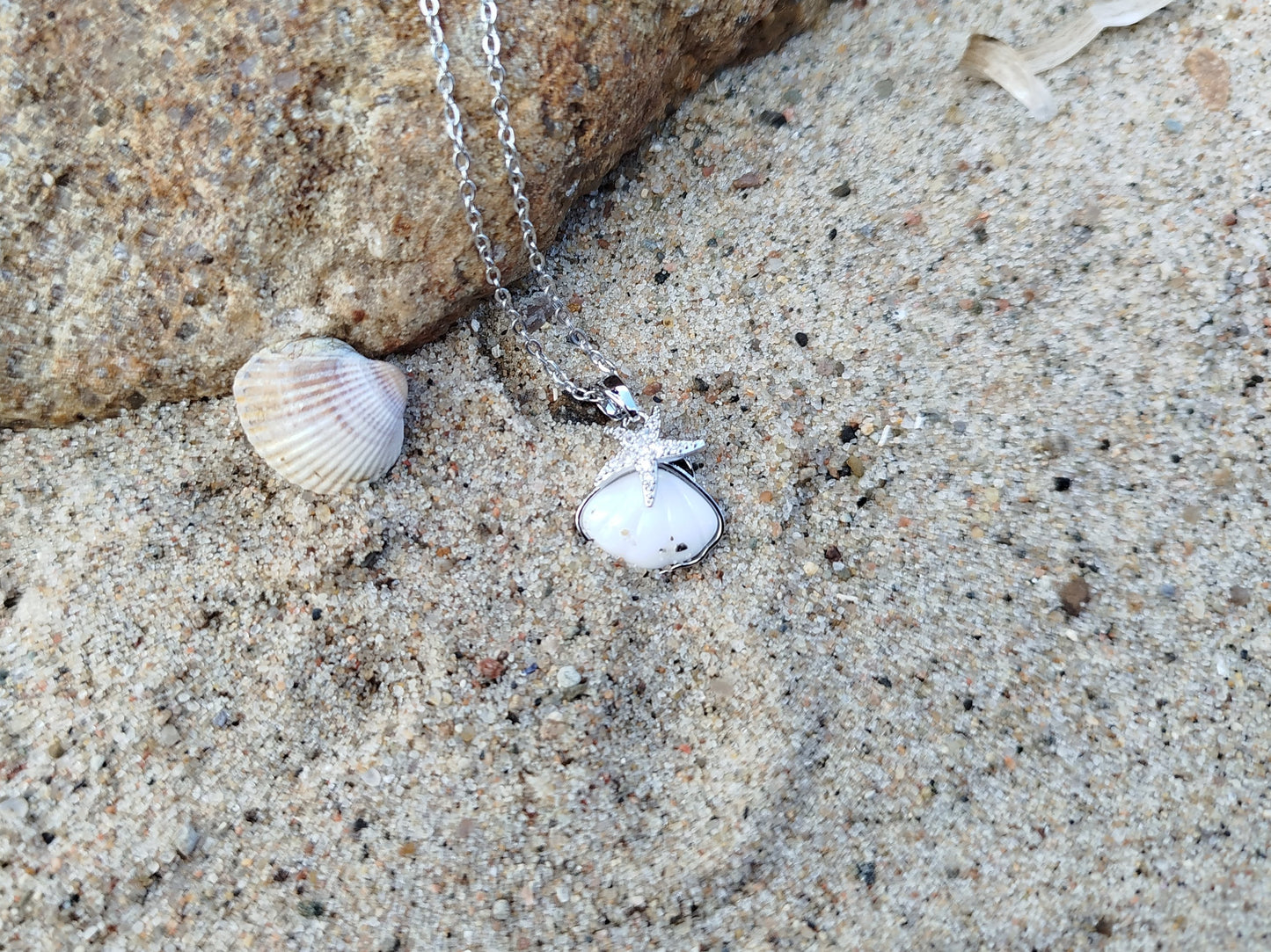 Necklace with a pendant on sand next to a rock