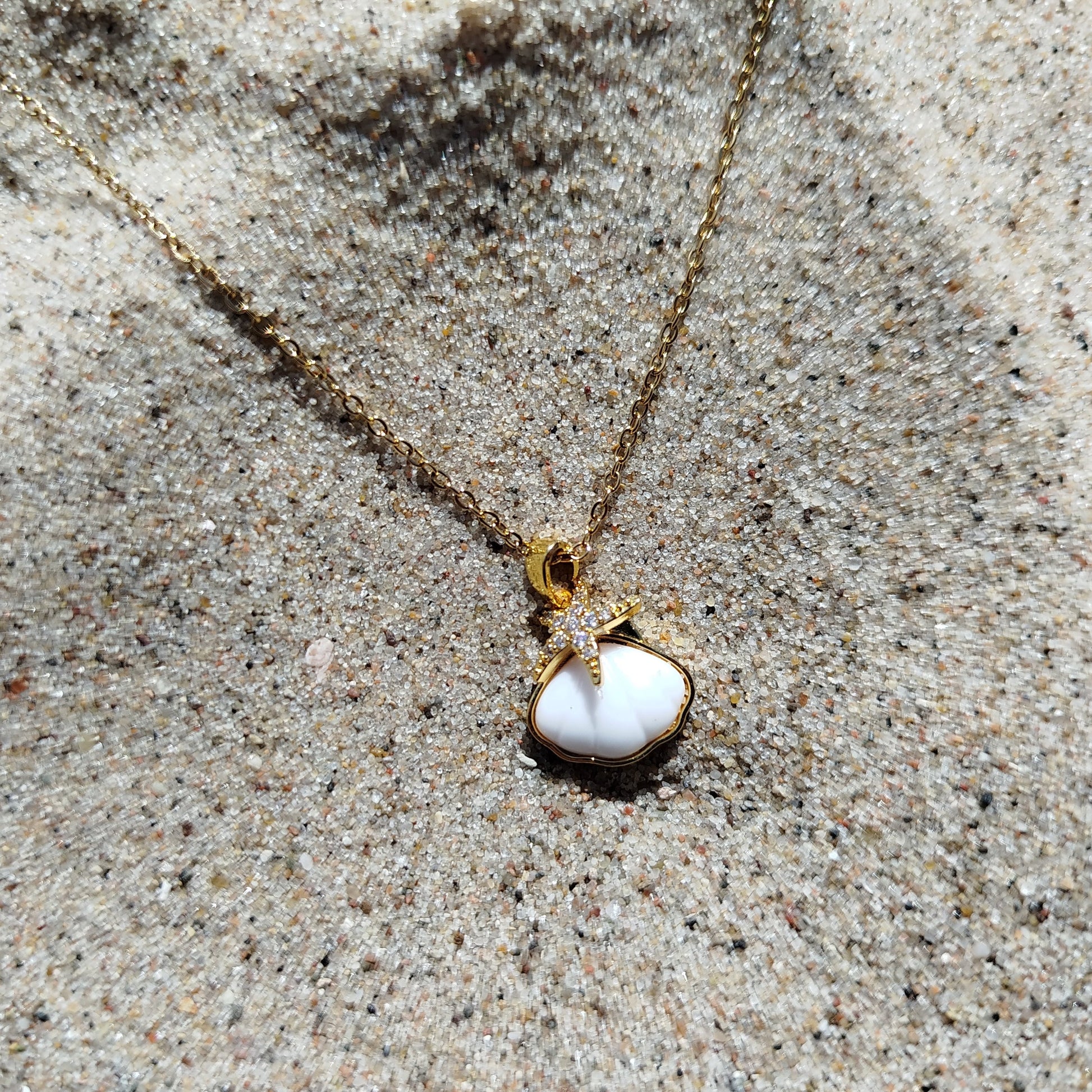 Gold necklace with a pendant on sandy surface