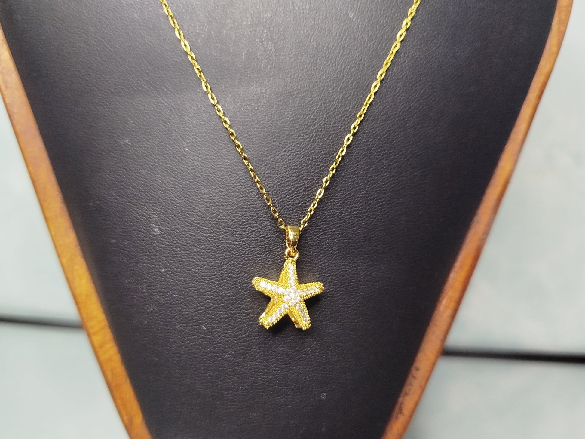 Gold star-shaped pendant necklace on a black mannequin bust.