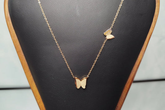 Gold butterfly necklace on a black jewelry display