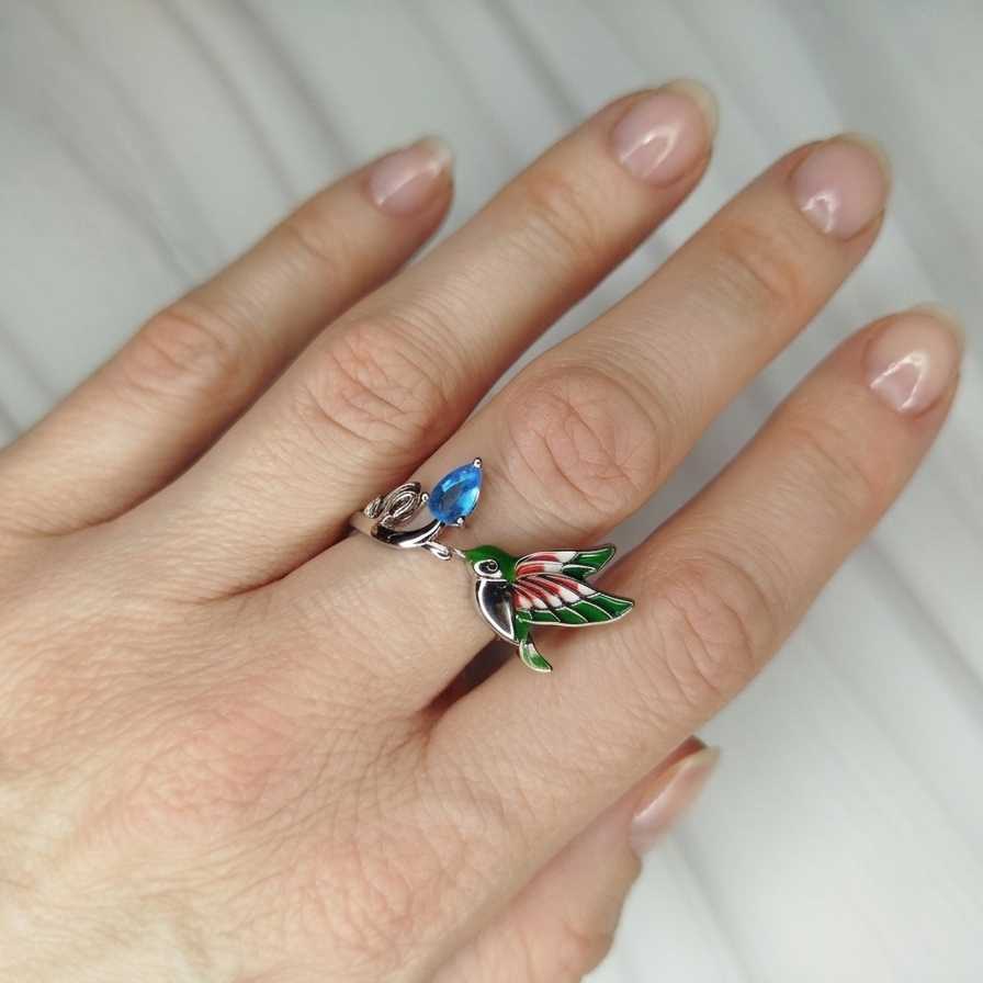 Hand wearing a decorative ring with a colorful bird design 